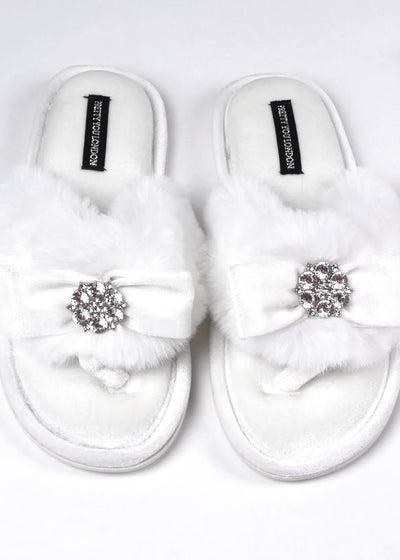 The Cream Rhinestone Toe Post Slippers are the ultimate glam house shoes! This open-toe post style is so comfy, as well as, elegant! A bow adorned with rhinestones sits above a super soft faux fur band. The crushed velvet padded footbed gives irresistible comfort, and the no slip sole gives long wearability.   