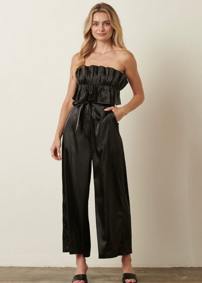 This luxurious Black Satin Tie Back Jumpsuit features a ruffle around the bust.  Grab attention while being comfortable in this super silky jumpsuit!  A perfect outfit for any special occasion!