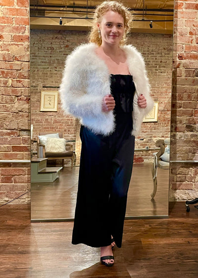 Stay warm with style in our White Jacket of Marabou!  This jacket features a round neckline, long sleeves, and cropped hem. The concealed hook-eye fastenings create an elegant look.  The quality feathers and satin lining keep this jacket super soft.   Perfect piece to compliment a wedding gown, as well as, your comfy jeans.