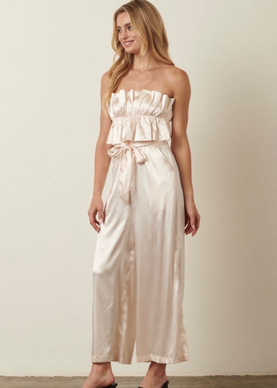 Steal the show with this Champagne Satin Tie Back Jumpsuit! The super cute ruffle on the bust and gorgeous tie back detail will grab attention! This comfortable jumpsuit  makes a perfect outfit for a bride to be!  Bridal shower, rehearsal dinner, or bachelorette trip, this jumpsuit will fit any occasion!